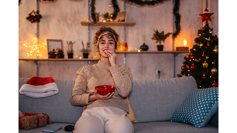 Woman watching movie and eating snacks at Christmas