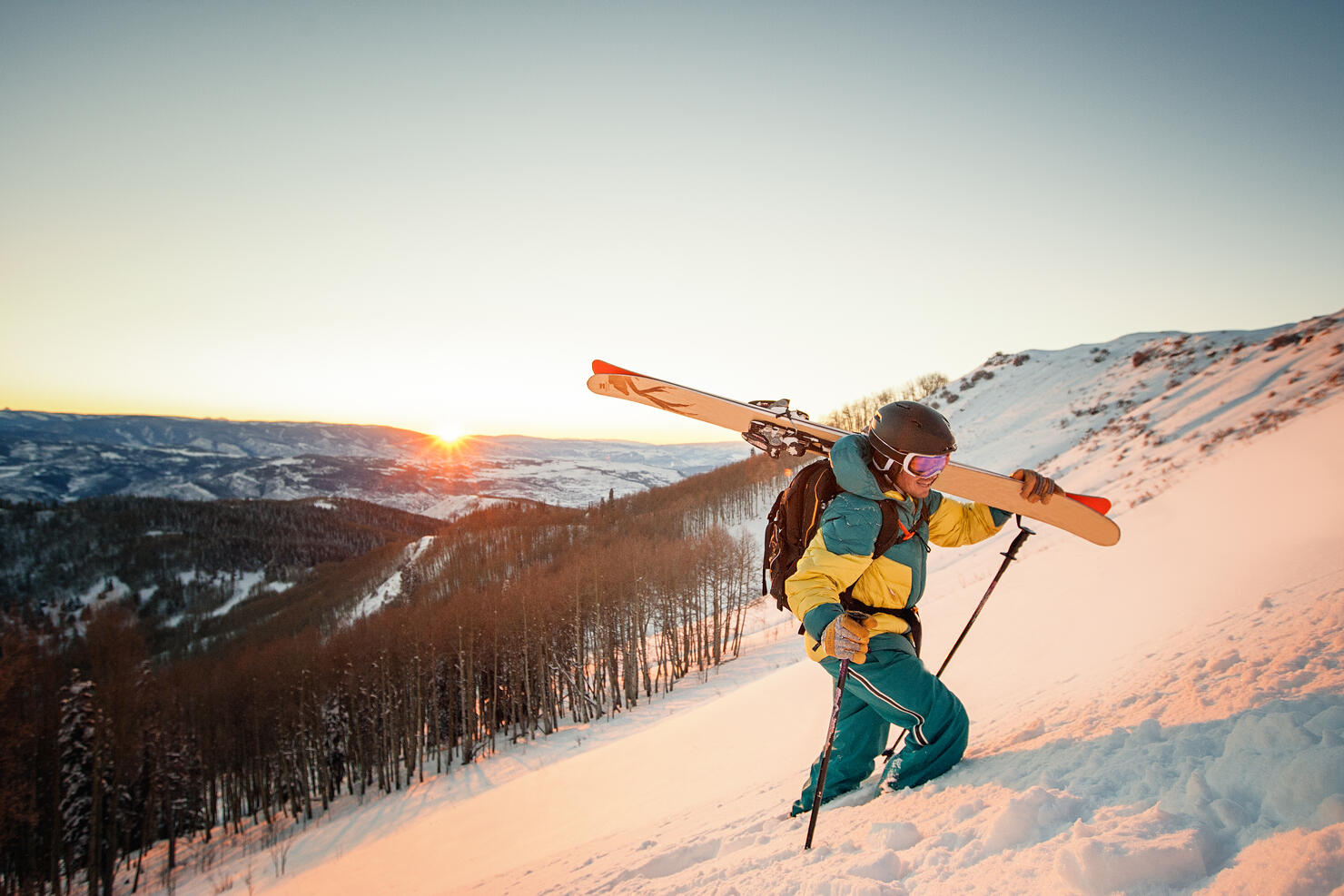 Guy with skis hiking during sunset in Colorado.