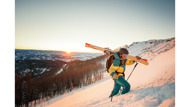 Guy with skis hiking during sunset in Colorado.