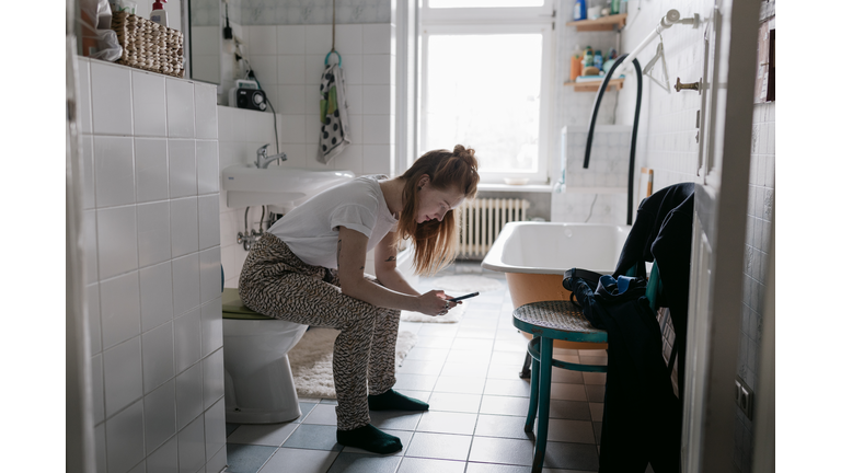 Girl In Bathroom At Home Using Smartphone