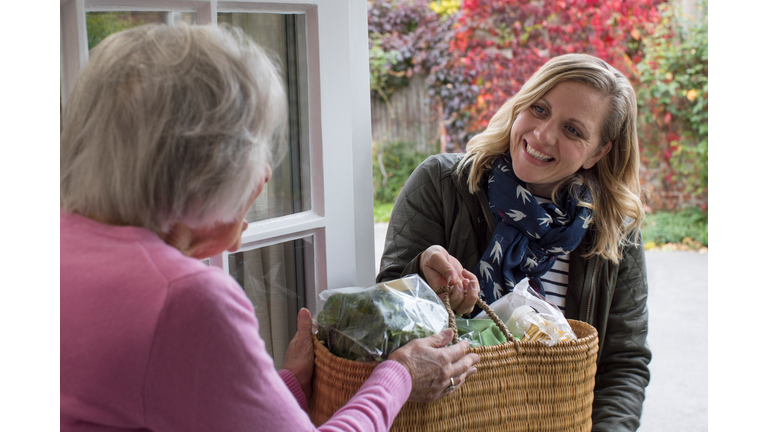Female Neighbor Helping Senior Woman With Shopping