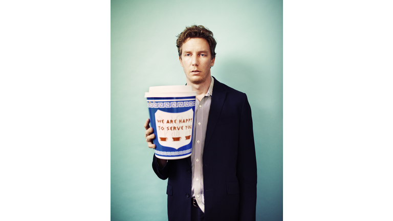 Tired man holding giant cup of coffee