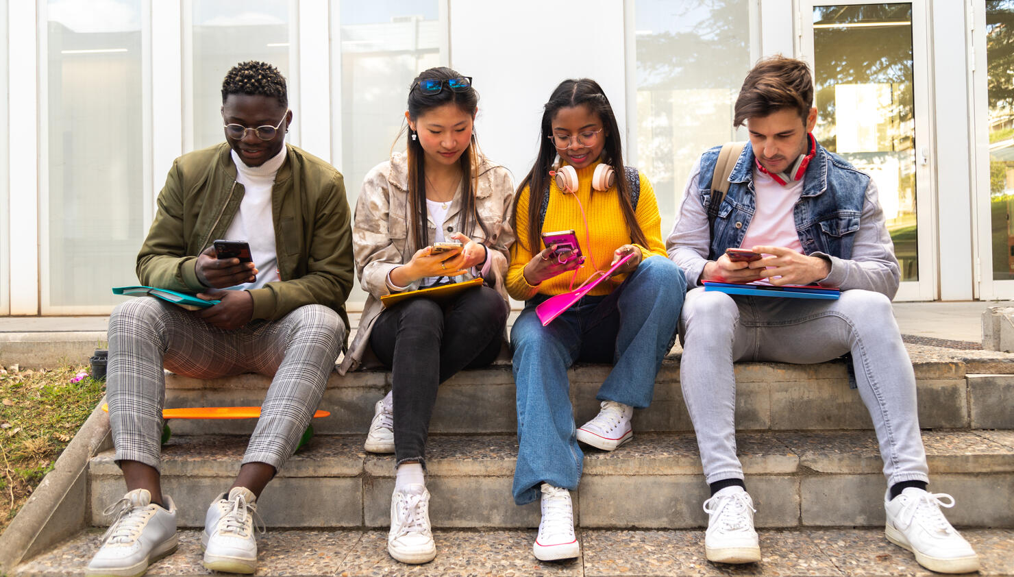 Group of multiracial teenage college friend students ignoring each other looking at mobile phone. Smartphone addiction.