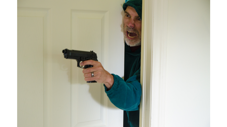 Armed man looking out of bedroom door