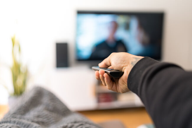 man on sofa changing TV channel