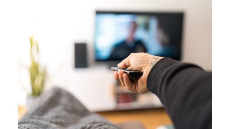 man on sofa changing TV channel