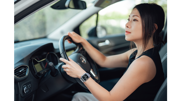 Side view of young Asian woman driving a car