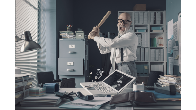 Crazy businessman destryoing his office with a baseball bat