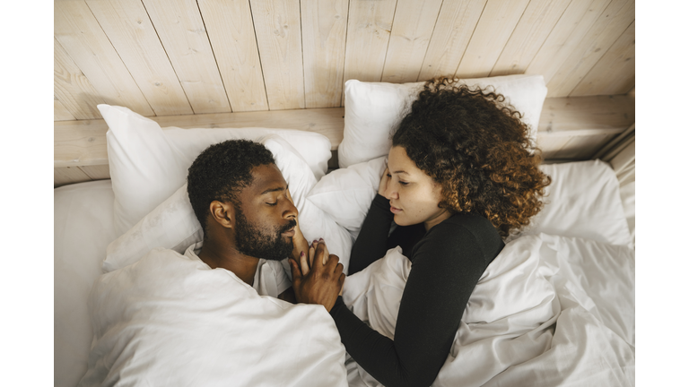 Directly above view of couple sleeping on bed in hotel