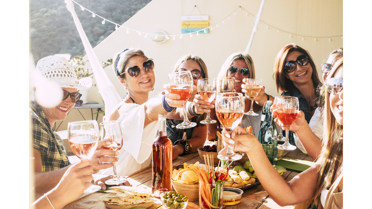 Cheerful group of happy female people clinking and toasting together with friendship and happiness - young and adult women have fun eating - food and beverage celebration concept