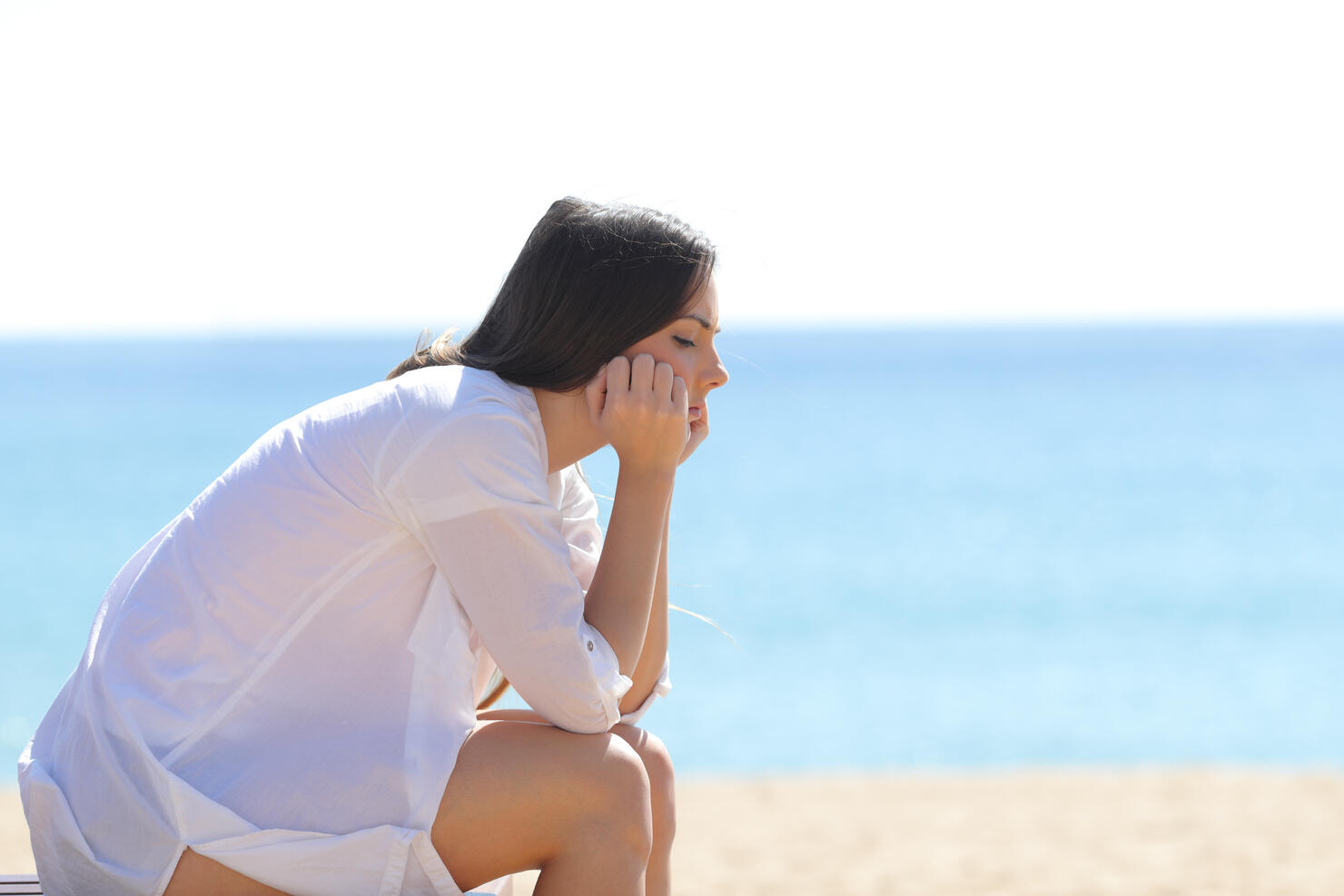 Profile of a worried woman sitting on the beach