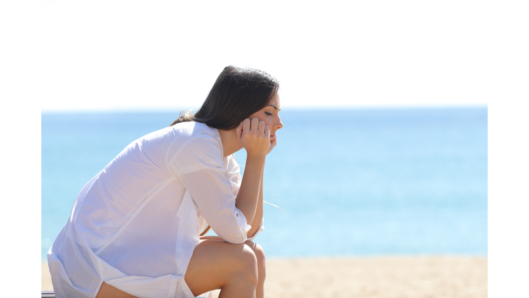 Profile of a worried woman sitting on the beach