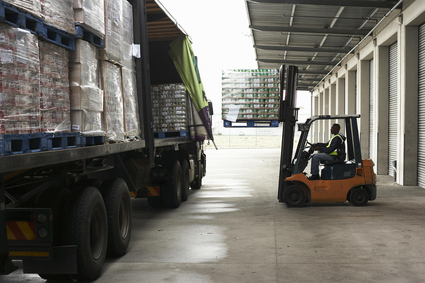Man operating forklift truck loading pallets onto lorry