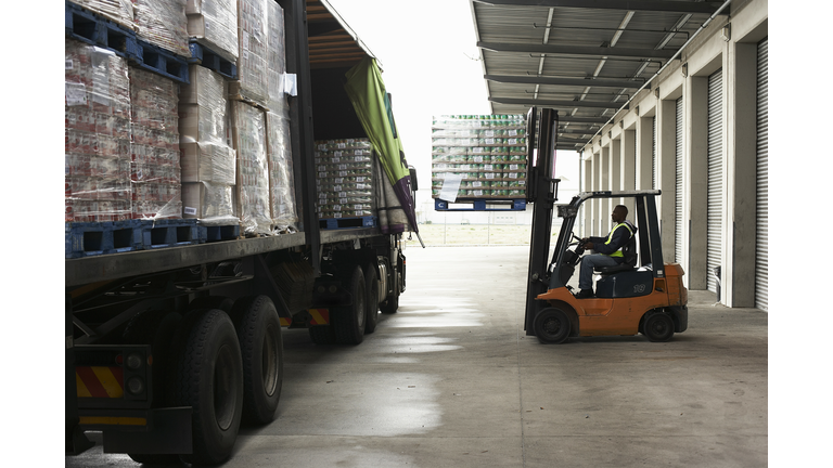 Man operating forklift truck loading pallets onto lorry