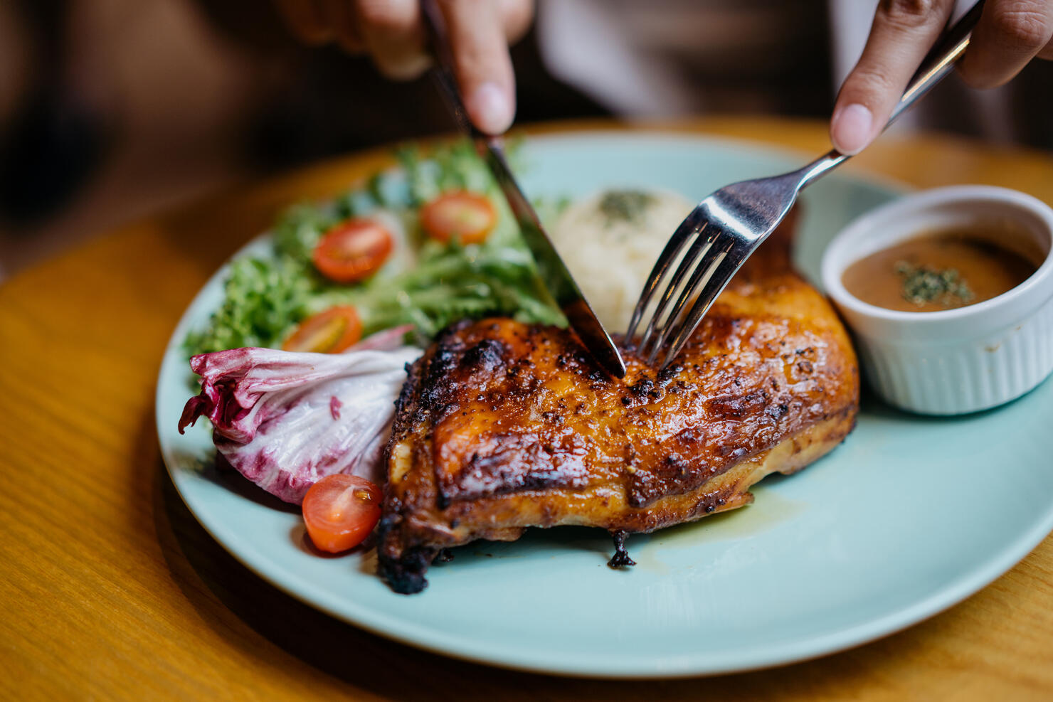 An asian woman enjoying a grilled chicken meal in restaurant