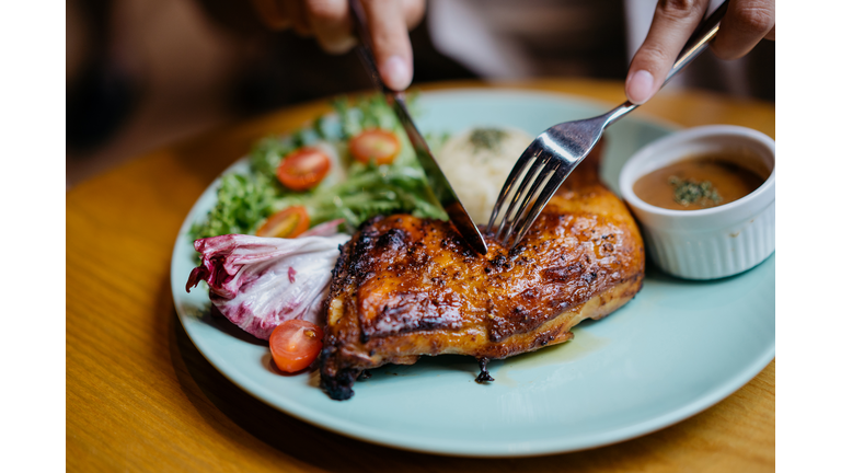 An asian woman enjoying a grilled chicken meal in restaurant