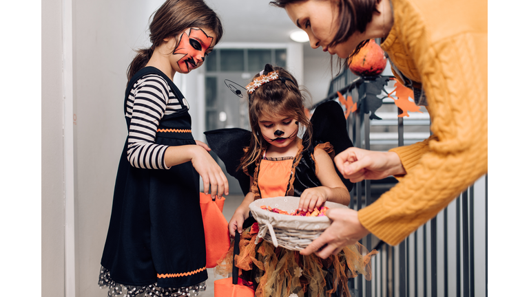 Girls dressed in Halloween costumes collecting candies in the neighborhood