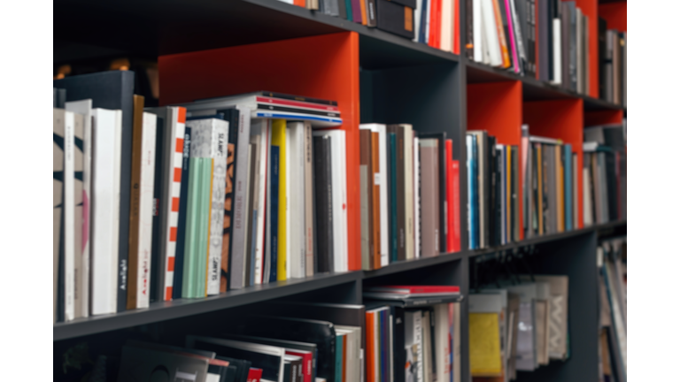 Blurred background with multi-colored books and catalogs on the shelves