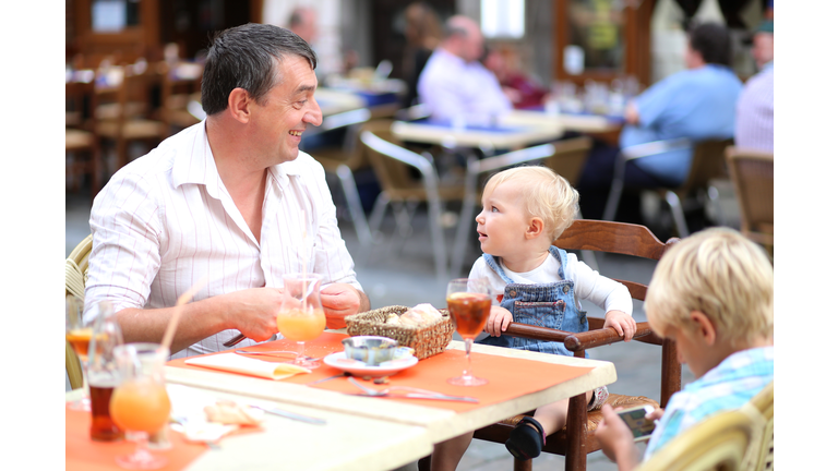 Family eating and drinking in outdoors italian cafe