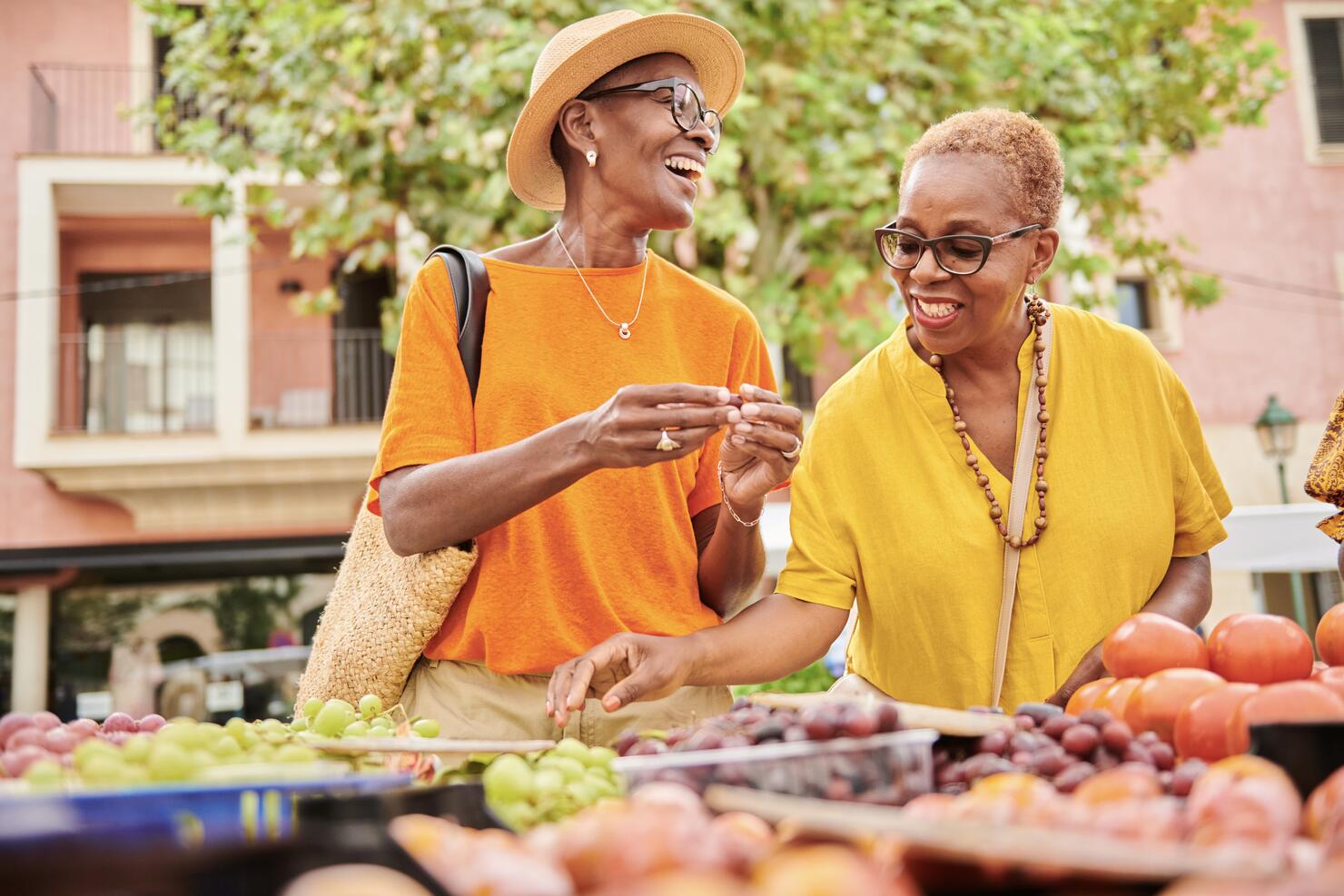 Two mature women shopping together at an outdoor food market
