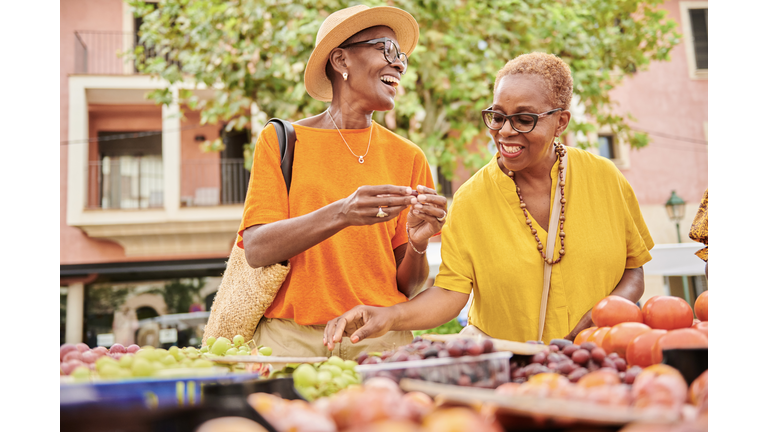 Two mature women shopping together at an outdoor food market