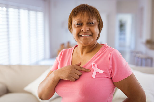 African american senior woman pointing at breast cancer awareness ribbon on pink t-shirt