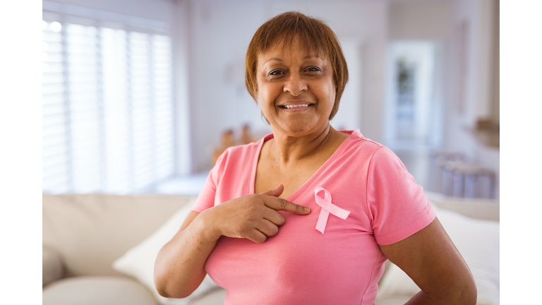 African american senior woman pointing at breast cancer awareness ribbon on pink t-shirt