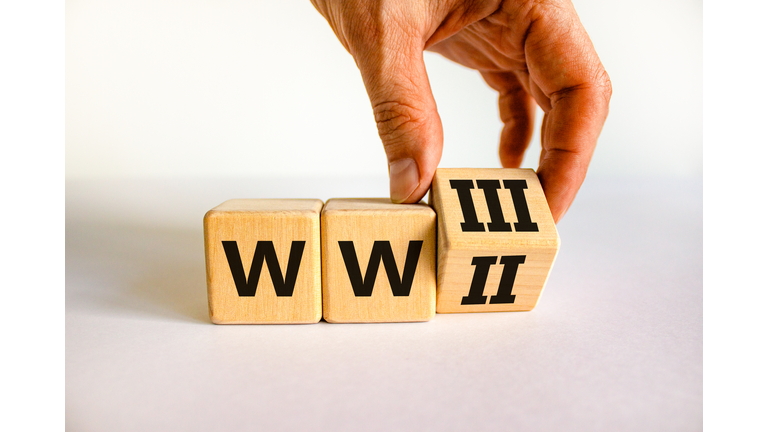 WW3 world war 3 symbol. Businessman turns the wooden cube and changes the concept word WW2 to WW3. Beautiful white table white background, copy space. Business WW3 world war 3 concept.