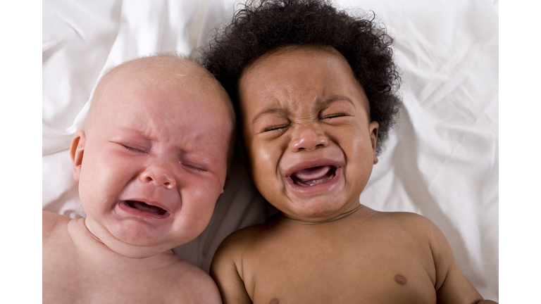 Faces of two multiracial babies crying together