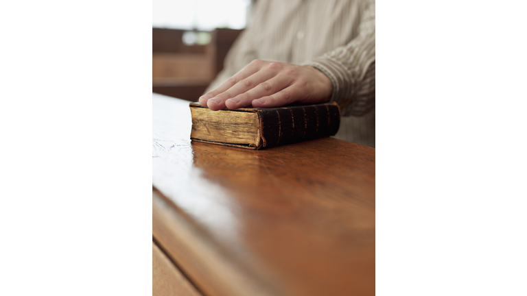 Hand of witness on Bible in courtroom