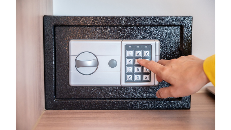 Someone hand trying to press passwords on safety lock pad for open a safety box.