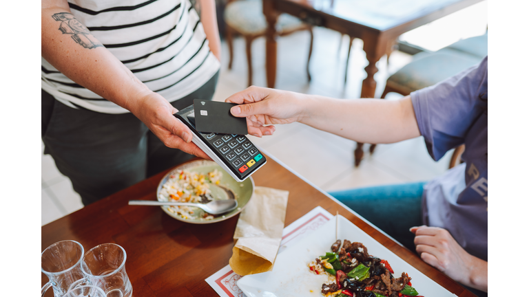 Contactless payment in restaurant. Wireless card reader scanning credit card from customer hand in cafe, high angle view