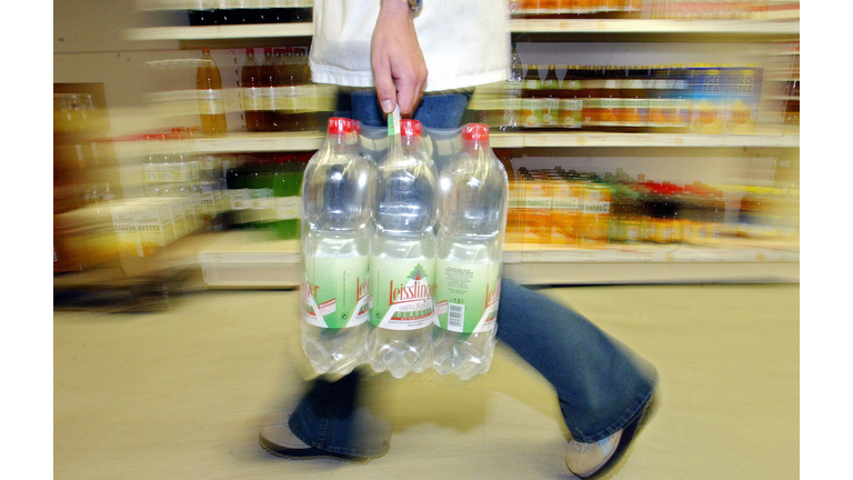 A person carries a six-pack of plastic m