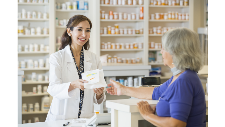 Pharmacist giving prescription to customer