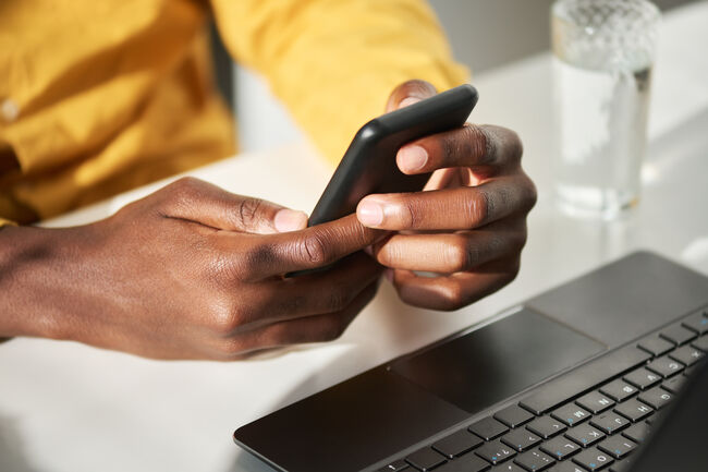 Hands of young African American businessman holding mobile phone