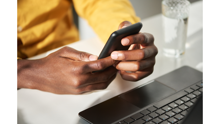 Hands of young African American businessman holding mobile phone