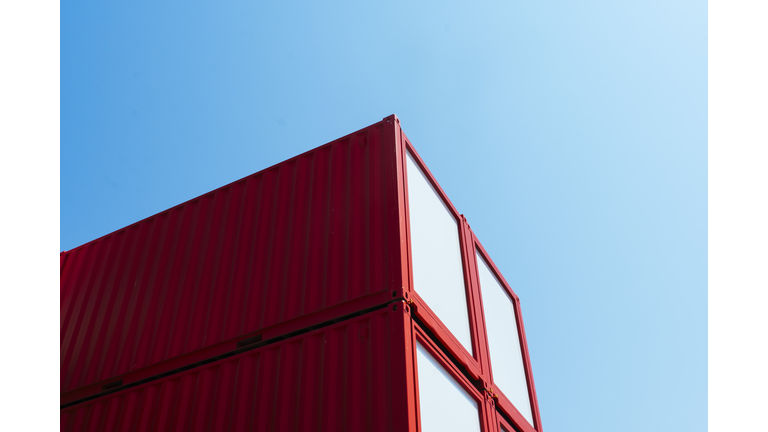 Close-up of repurposed red shipping containers with clear blue sky