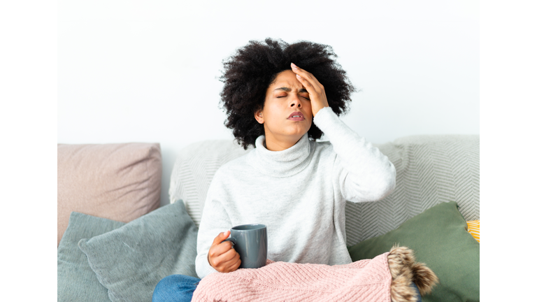 Woman gesturing headache sitting on the sofa