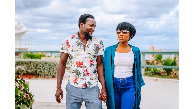 Happy cute young African American couple hold hands on a vacation or on honeymoon in a tropical location