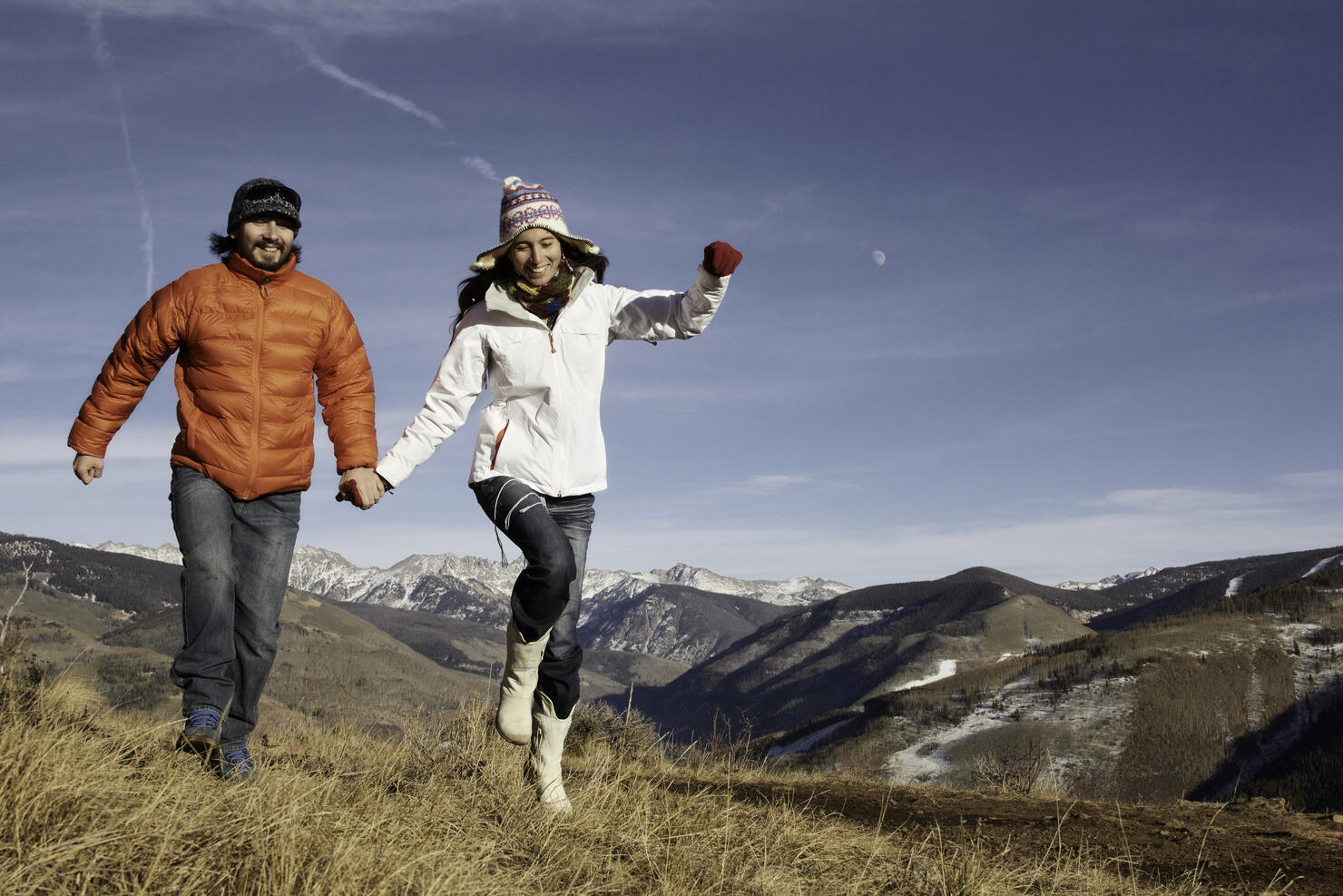 Couple holding hands and running in the mountains.