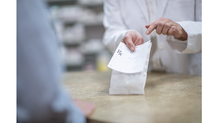 Pharmacist Holding Out a Packaged Prescription stock photo