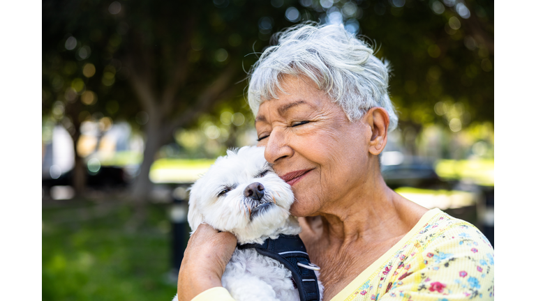 A mixed race senior woman holding her puppy outdoors