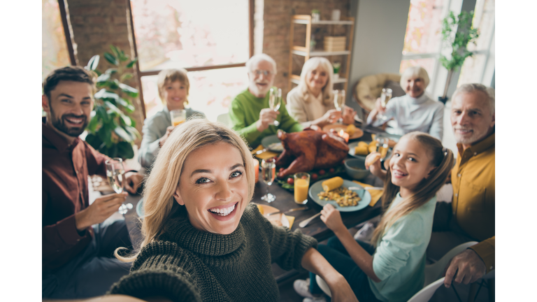 Photo of big family sit feast dishes table around roasted turkey multi-generation relatives making group selfies raising wine glasses juice in living room indoors