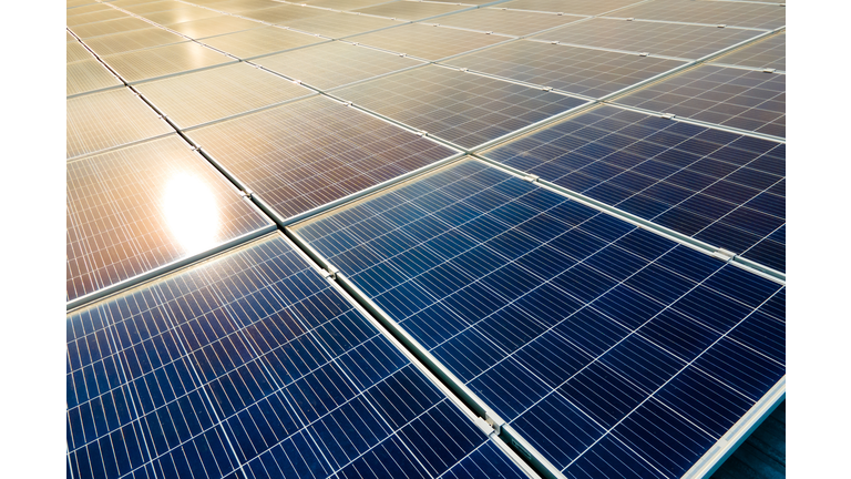 Aerial view of surface of blue photovoltaic solar panels mounted on building roof for producing clean ecological electricity. Production of renewable energy concept.