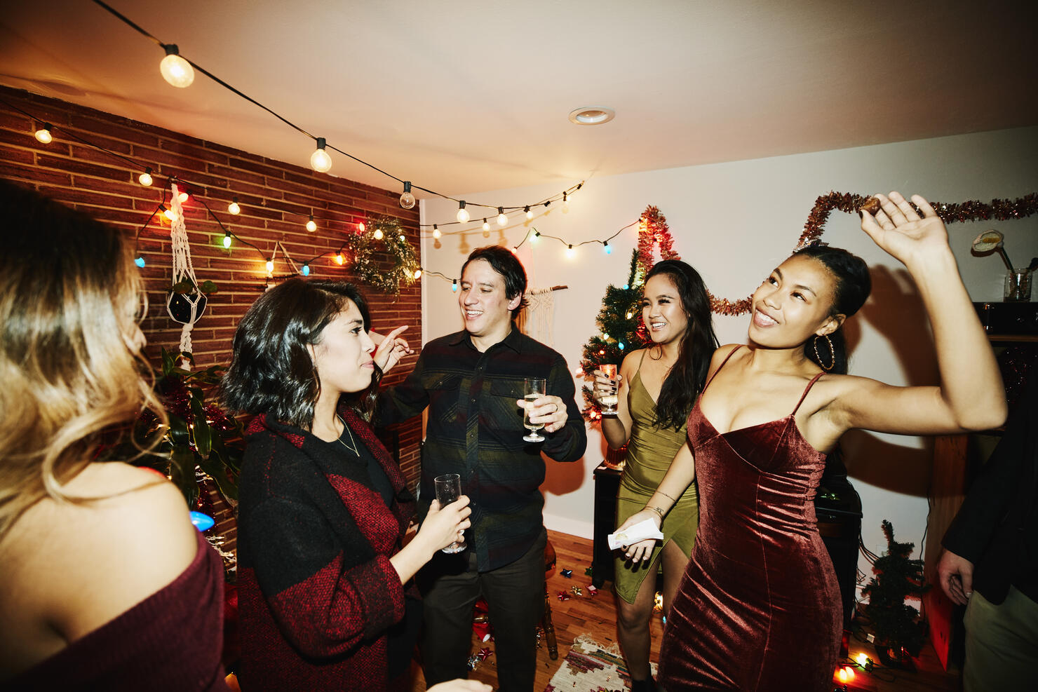 Smiling friends dancing together in living room during holiday party