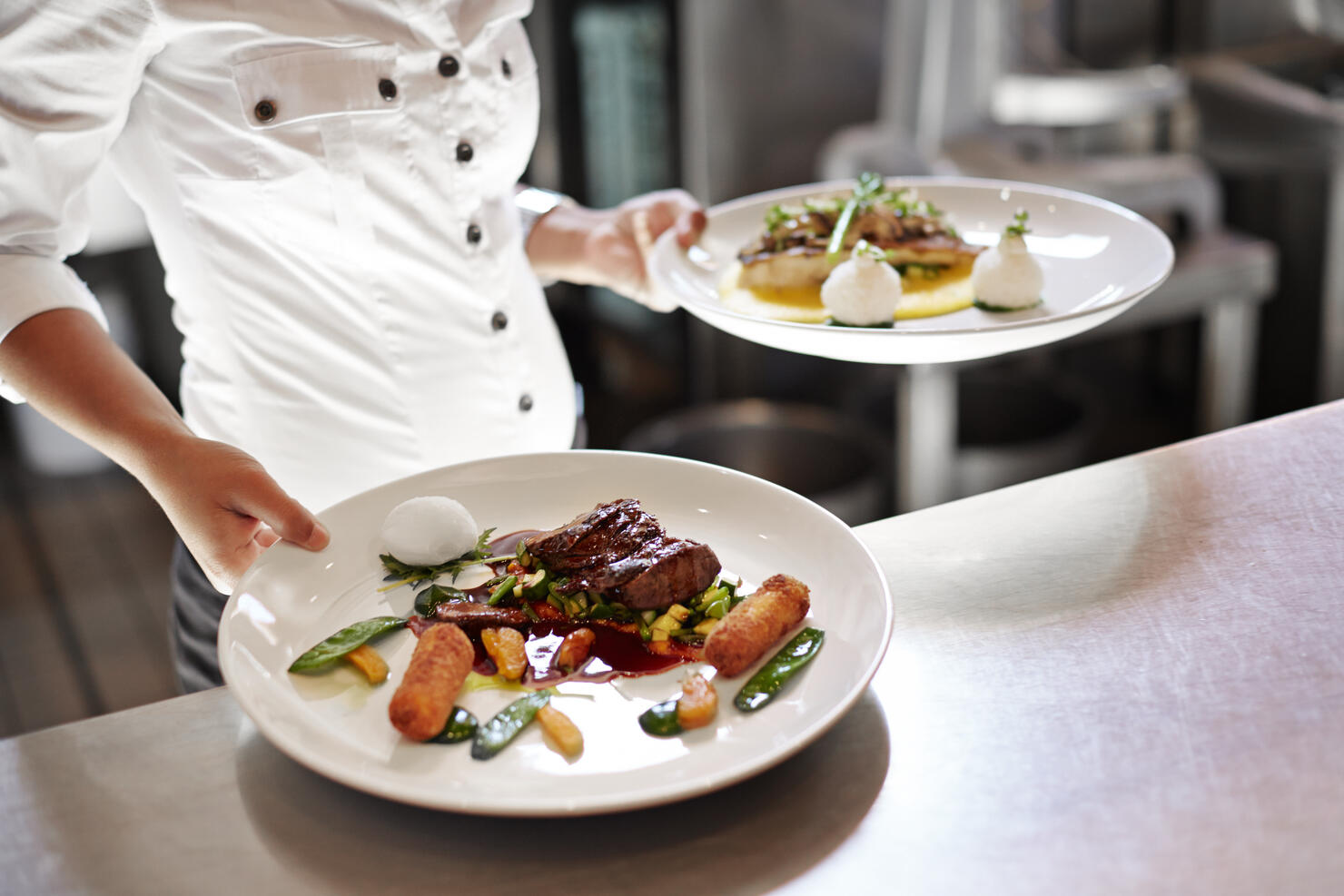 Waiter picking up dishes in kitchen at restaurant