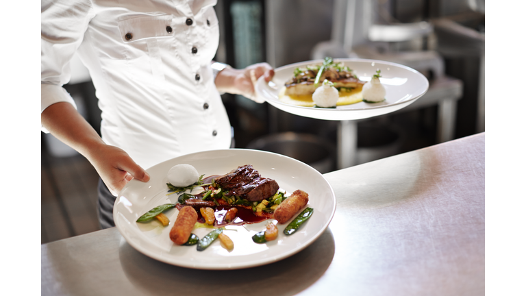 Waiter picking up dishes in kitchen at restaurant