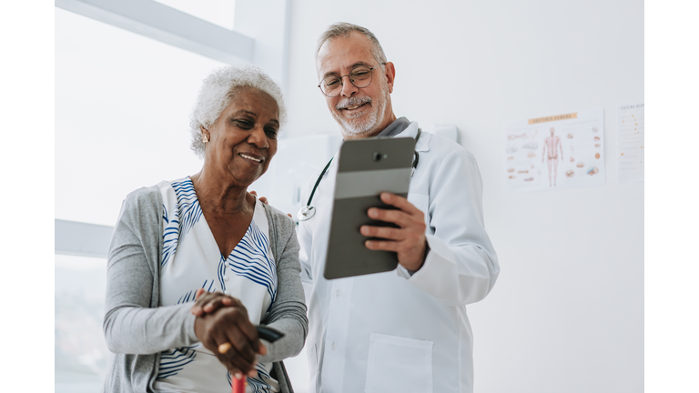 Doctor attending senior patient using digital tablet