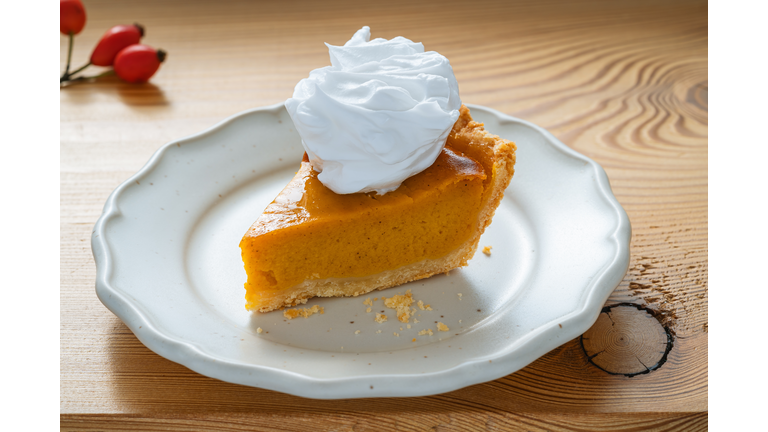 Thanksgiving day autumnal dessert , slice of freshly baked pumpkin pie with whipped cream