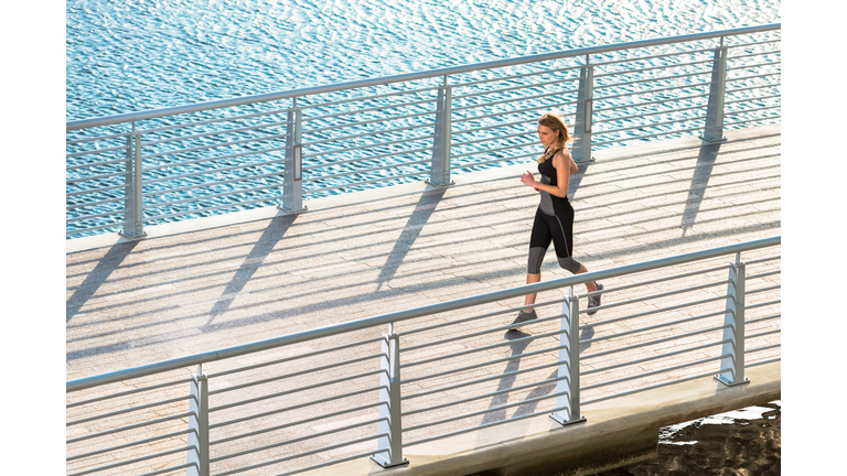 Young woman running on bridge